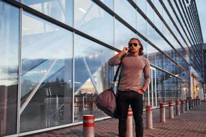 Guy in sunglasses talking on the mobile phone on building at background photo