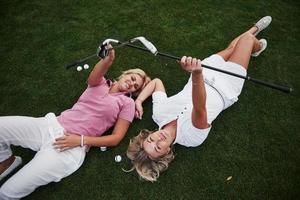 Dos chicas se acuestan en el campo de golf y se relajan después del juego.