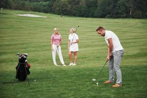 grupo de elegantes amigos en el campo de golf aprende a jugar un nuevo juego foto