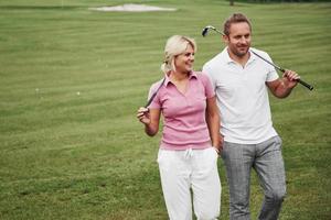 Sportive couple playing golf on a golf course, they stand to the next hole