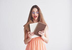 Education concept. Photo of young woman in the glasses and red lips holding the books