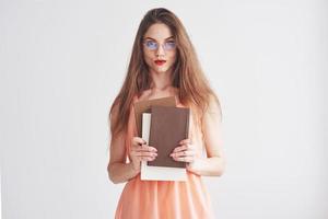 Foto de mujer joven con gafas y labios rojos sosteniendo los libros