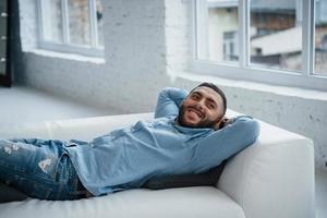 Young guy with beard smiling and has resting while lying on the bed