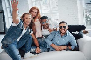 Good wearing people. Beautiful people sitting at the sofa with windows at background photo