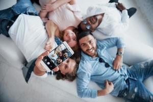 Sincere smiles. Young people laying down and take a selfie with focus on the phone photo