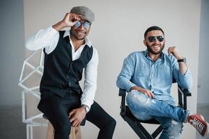 Sit in a good mood. Photo of mixed race bearded friends have photoshoot in the studio