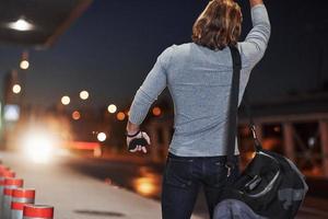 Pick me up please, I must be in airport right now. Young man with bag trying to stop the car because he's late photo