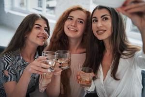 Three beautiful girls takes selfie with drinks in their hands photo