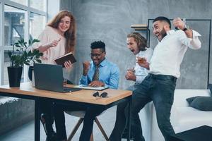 Ripped of jackpot in business. Group of multiracial office workers in formal clothes talking about tasks and plans photo