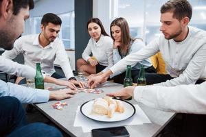 Relaxing with game. Celebrating successful deal. Young office workers sitting near the table with alcohol photo