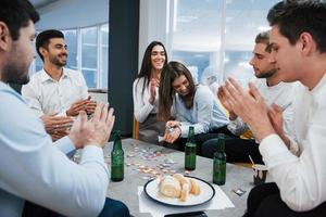 Good joke. Celebrating successful deal. Young office workers sitting near the table with alcohol photo