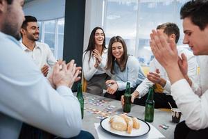 Everyone is smiling. Celebrating successful deal. Young office workers sitting near the table with alcohol photo