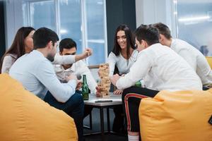 agradable velada en buena compañía. celebrando un trato exitoso. jóvenes trabajadores de oficina sentados cerca de la mesa con alcohol foto