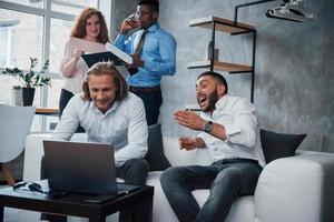 Joyful news. Group of multiracial office workers in formal clothes talking about tasks and plans photo