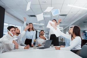 All papers up in the air. Job is done. Group of office workers happy to hit their own records and being successful photo