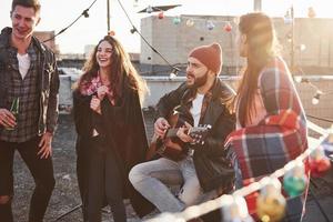 Enjoying the company of each other. Rooftop party with alcohol and acoustic guitar at sunny autumn day photo