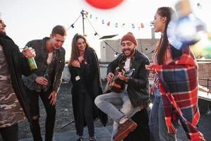 Califica esta canción. Fiesta en la azotea con alcohol y guitarra acústica en el soleado día de otoño foto