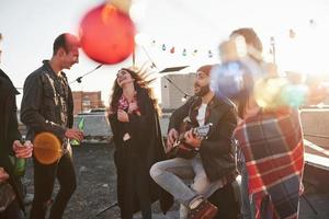 Colorful light bulbs. Rooftop party with alcohol and acoustic guitar at sunny autumn day photo