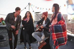 pieza de arte musical conmovedora. Fiesta en la azotea con alcohol y guitarra acústica en el soleado día de otoño foto