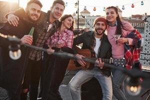 Lovely young people. Party at the rooftop. Five good looking friends that posing for the picture with alcohol and guitar photo