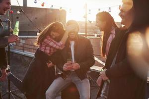 Awesome sunshine. Young couple having fun with friends on the rooftop. Girl covers guy's face photo