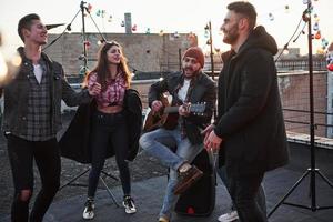 Looks like emotional song. Acoustic guitar playing and singing at the rooftop at the sunset photo