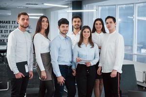 despues del trabajo. Retrato de equipo joven en ropa clásica en la moderna oficina bien iluminada foto