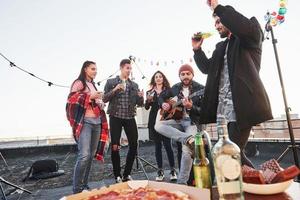 Enjoying the song. Table with food. Weekend on the rooftop with guitar, alcohol and pizza photo