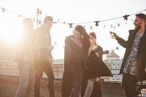 Cheerful people. Rooftop party with alcohol and acoustic guitar at sunny autumn day