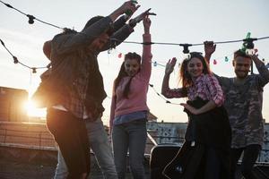 fiesta de baile en la azotea con un hermoso sol de fondo. gente joven con estilo foto