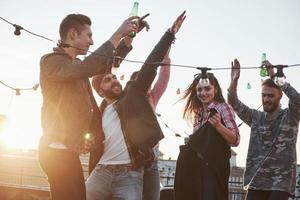 calor otoñal. fiesta de baile en la azotea con un hermoso sol de fondo. gente joven con estilo foto