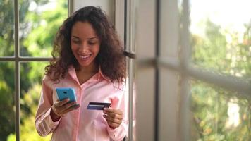 bella donna latina che utilizza smartphone e tiene una carta di credito video
