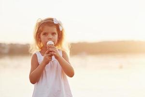 Linda niña comiendo helado en el fondo del lago y el bosque foto