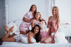 Happy together. Cute girls have meeting and holiday in the awesome lighted room with white walls and bed. Chocolate cookies in the hands photo