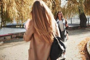 Two young friends are glad to meet each other at park after the studying photo