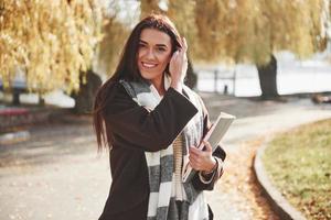 Sincere student smiles. Cheerful beautiful brunette girl holds notepad while have a rest after studying photo