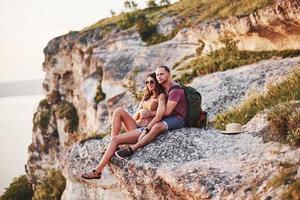 Awesome view. Young couple resting from walking at the edge of the mountain. Wonders how far other coast is it photo