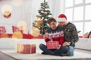 que hay ahi. El hombre sorprende a su esposa para Navidad en la hermosa habitación con adornos navideños. foto