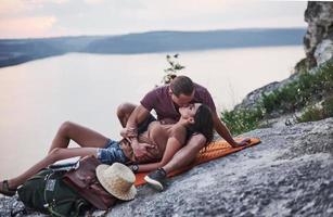 Gentle emotions. Young couple have decided to spend their holiday in active way on the edge of the gorgeous rock with lake at background photo