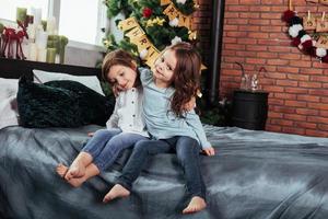 This is truly friendship. Kids sits on the bed with decorative background. Conception of new year