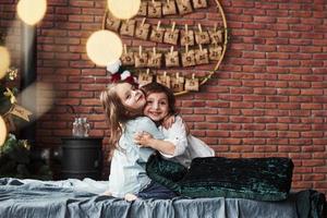 Always together. Little girls having fun on the bed with holiday interior at the background photo