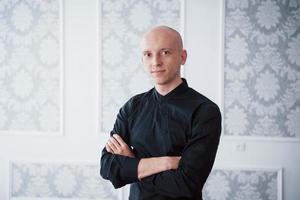 Beautiful lighting. Portrait of cheerful guy in the classic black shirt with arms crossed photo