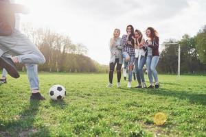 un grupo de amigos en ropa casual juega al fútbol al aire libre. la gente se divierte y se divierte. descanso activo y puesta de sol escénica foto