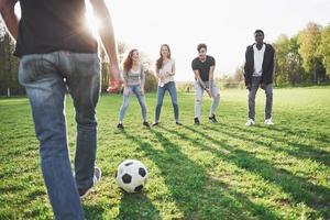 A group of friends in casual outfit play soccer in the open air. People have fun and have fun. Active rest and scenic sunset photo