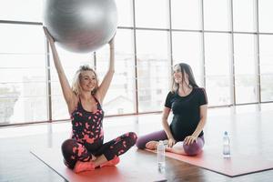 Young pregnant women sitting on carriages and holding a bullet for exercises photo