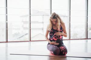 concepto de embarazo de yoga y fitness. retrato de una joven modelo de yoga embarazada que se está desarrollando en interiores. foto