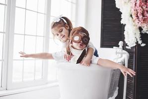 Portrait of a girl and a boy in pilot hat playing in bathroom at pilots or sailors. The concept of travel, childhood and the realization of dreams photo