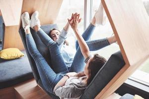 Beautiful young girl spends her time in the recreation area. She sits and has fun in the sofa chair in the form of a hexagon with pillows near the window photo