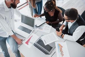 jóvenes empleados sentados en la oficina en la mesa y usando una computadora portátil, un concepto de reunión de intercambio de ideas de trabajo en equipo. foto