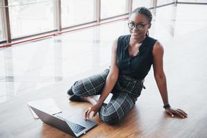 una joven mujer afroamericana está feliz con una computadora portátil. foto